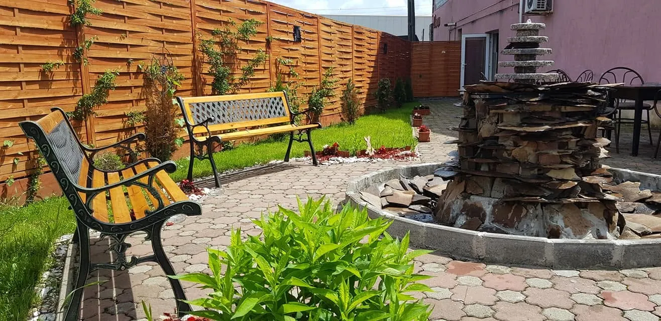Curtea cu fântâna din piatră și bancă din fier forjat